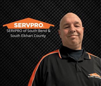 man smiling at camera with black background and servpro logo 