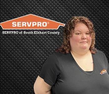 woman smiling at camera while standing next to a SERVPRO logo