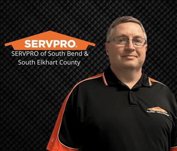 man smiling at cameras with glasses on, black background and a servpro logo
