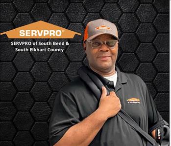 man looking at camera with a black background and an orange SERVPRO logo