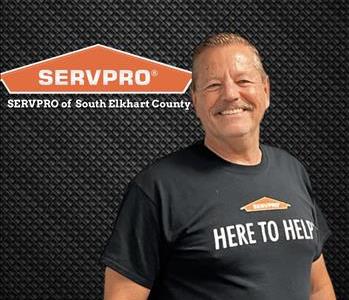 man in black t shirt smiling at camera standing next to a SERVPRO logo 
